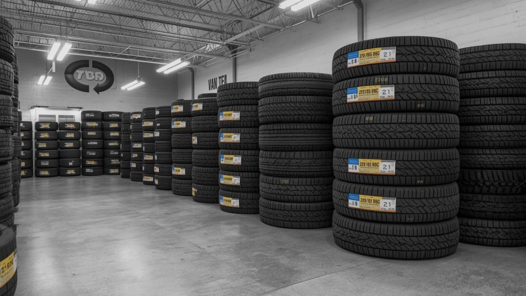 Mechanic fitting a new tyre in a garage in Kettering with mobile tyre van and tyre stacks, representing same day tyre fitting service