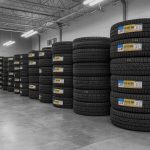 Mechanic fitting a new tyre in a garage in Kettering with mobile tyre van and tyre stacks, representing same day tyre fitting service