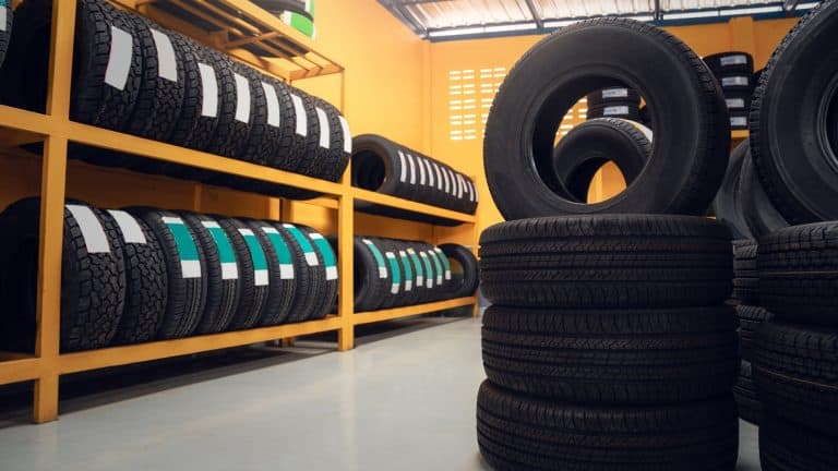 Mechanic fitting premium tyres on a car in a modern garage.