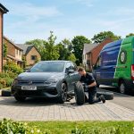 Mobile tyre fitter replacing tyre at home in Northampton with service van and residential setting